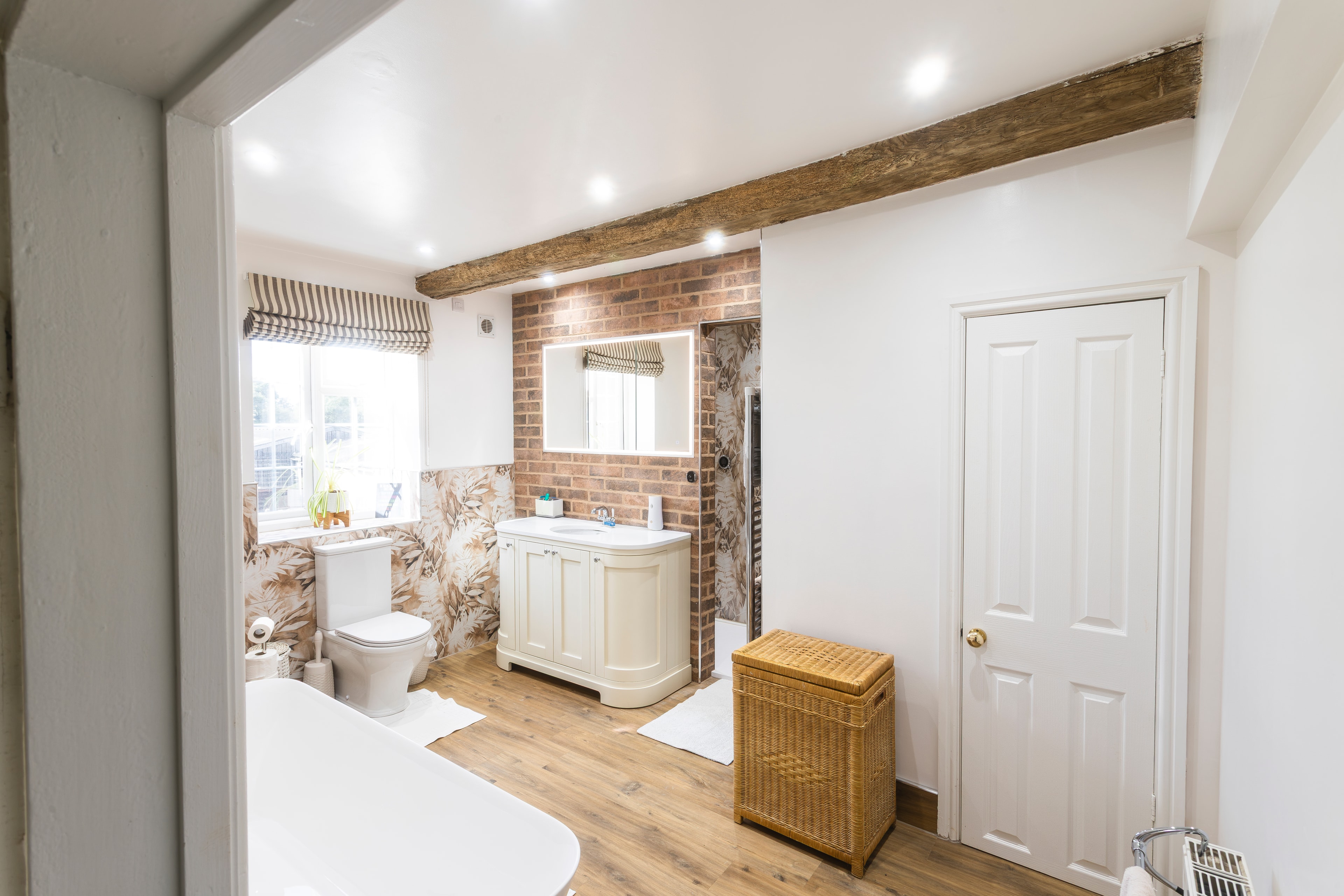 View through doorway into rustic bathroom with botanical tiles and curved vanity